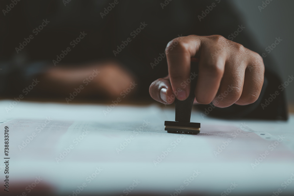 Poster sign approved stamp on document to permit and certify for work document and visa at desk.