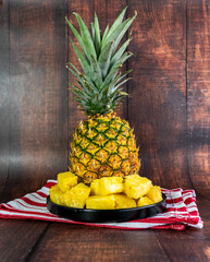 Pineapple slices on a black plate on a wooden table. Healthy fruit.