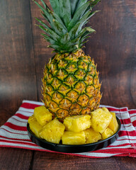 Pineapple slices on a black plate on a wooden table. Healthy fruit.