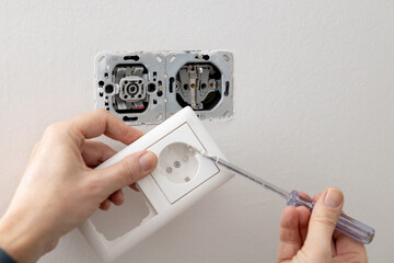 Light switch and socket are secured to a white painted wall