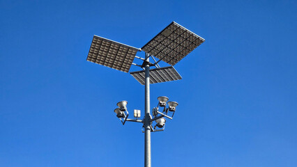 Massive strong light grey metal pole holding modern LED street light reflectors with sensors...