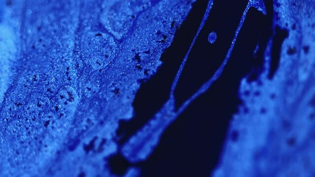 Glitter fluid spill. Paint mix. Defocused blue black color sparkling particles texture liquid ink flow cascade motion abstract art background.