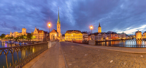 Panoramic night view of Fraumunster church and Munsterbrucke bridge over river Limmat in Old Town of Zurich, the largest city in Switzerland
