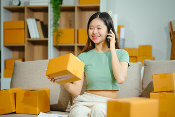 young Asian entrepreneur, the owner of a small clothing store, organizes online live streams showcasing products packaged in cardboard boxes, ensuring prompt and efficient delivery.