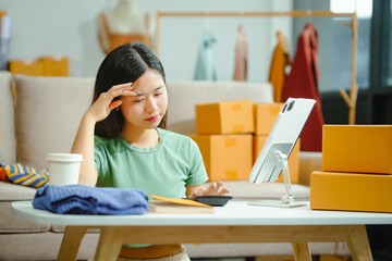 young Asian SME owner of a clothing store faces stress and sadness due to online challenges....