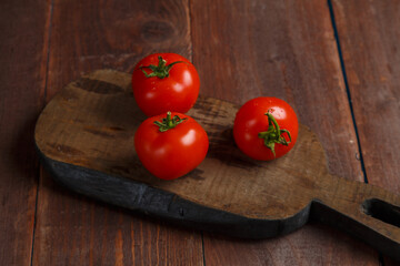 Red tomatoes on a wooden board on a table made of boards