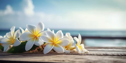 Zelfklevend Fotobehang Frangipani Flowers on a wooden table with sea and sky background. Plumeria Flowers. Beautiful floral background for greeting card, invitation, banner for Birthday, Summer Holiday, Spa, Resort © maxa0109