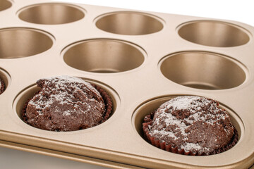 Two chocolate muffins in a metal baking dish, close-up.