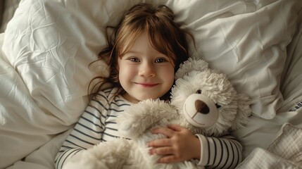 Child in striped pajamas lying in bed holding a bear, looking happy and cozy.