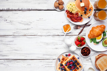 Breakfast or brunch side border on a white wood background. Top down view. Variety of sweet and...