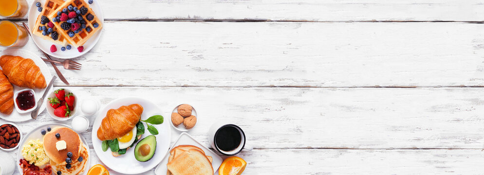 Breakfast or brunch corner border on a white wood banner background. Overhead view. Assortment of sweet and savory food items.
