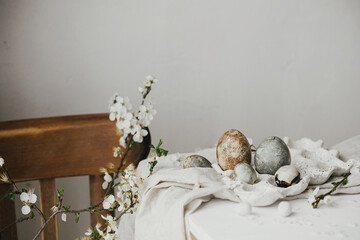 Fototapeta na wymiar Stylish easter eggs in tray and cherry blossom on rustic white table. Happy Easter! Easter country still life. Modern natural dye marble eggs and spring flowers, holiday banner