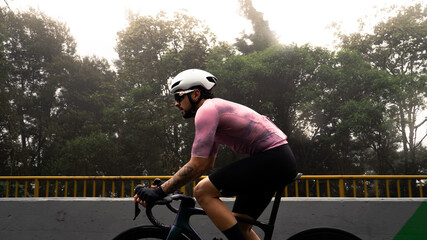 male cyclist with white helmet and pink jersey in side view riding a bicycle on a famous street in...