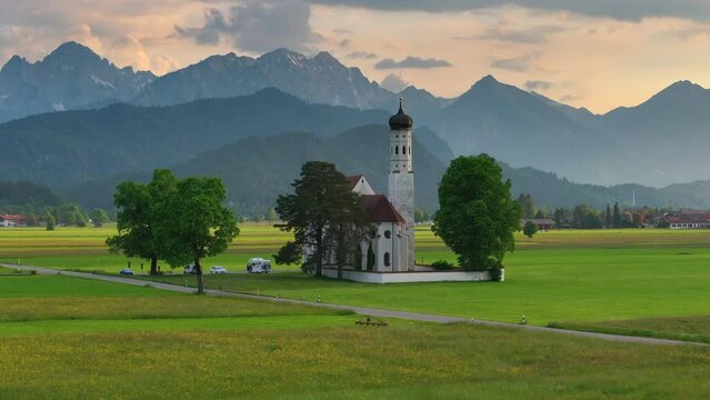 Drone wiew of the Saint Coloman church near the Neuschwanstein castle, against the backdrop of the beautiful mountains, Schwangau in the Bavarian province of Germany