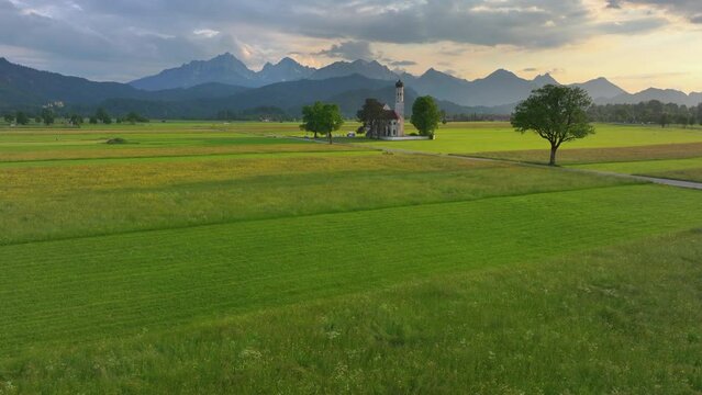 Drone wiew of the Saint Coloman church near the Neuschwanstein castle, against the backdrop of the beautiful mountains, Schwangau in the Bavarian province of Germany