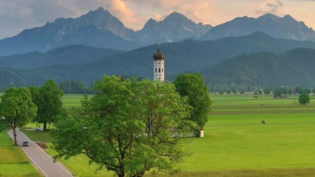 Drone wiew of the Saint Coloman church near the Neuschwanstein castle, against the backdrop of the beautiful mountains, Schwangau in the Bavarian province of Germany