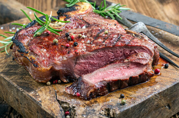 Traditional dry aged barbecue wagyu porterhouse beef steak sliced with herbs and salt served as close-up on a old rustic wooden board