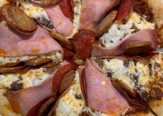 Macro image of pizza with ham, pepperoni, and sausage