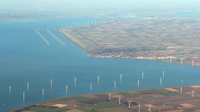 Aerial film of electric renewable energy wind mills or wind turbines in IJsselmeer, a large lake in the Netherlands, Holland, with dikes and polder visible, new land with meadows and blue water