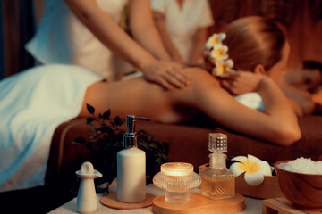 Aromatherapy massage ambiance or spa salon composition setup with focus decor candles and spa accessories on blur couple enjoying blissful aroma spa massage in resort or hotel background. Quiescent