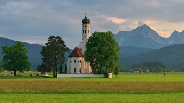 Drone wiew of the Saint Coloman church near the Neuschwanstein castle, against the backdrop of the beautiful mountains, Schwangau in the Bavarian province of Germany