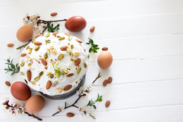 Easter cake decorated pistachios and almond nuts, easter eggs and spring branches on white wooden ...