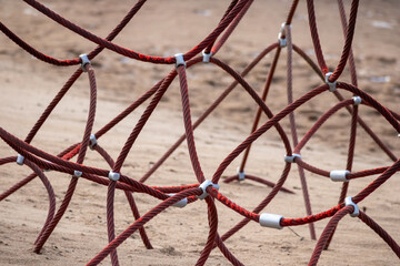 Red rope sections fastened with a metal clamp and a brown sand background