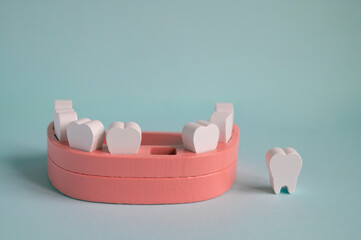 Toy wooden teeth and mouth on a turquoise background. Fall out, tooth loss medical concept. Model of a jaw with teeth. Dental health medical concept.	