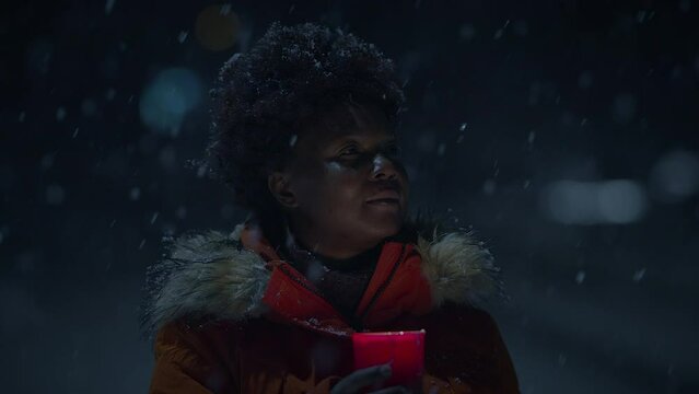 Black Female Person with Curly Hair Holding Candlelight in Snowy Winter Weather