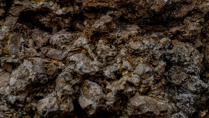 Soft spot focus. Rough textured close-up of a rocky stone wall surface with splashes. Rocky texture of natural stone. Grunge background