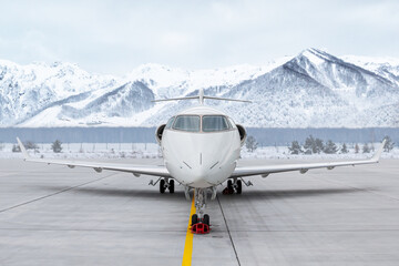 Front view of the modern white corporate airplane at the airport apron on the background of high...