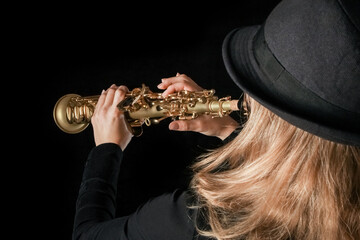 soprano saxophone in the hands of a girl on a black background