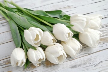 A beautiful bouquet of fresh white tulips laid on a wooden background.