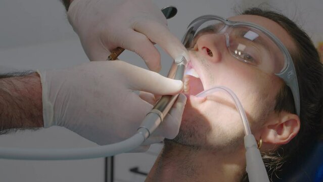 Close-up of a dental check-up with a patient being treated by a dentist with mouth suction and wearing protective goggles