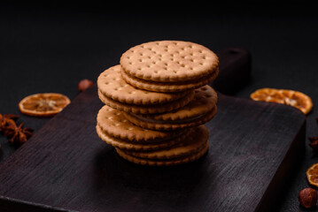 Round dotted snack snack cookies with cream on a dark concrete background