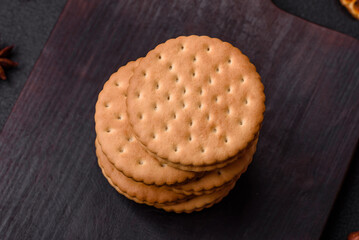 Round dotted snack snack cookies with cream on a dark concrete background