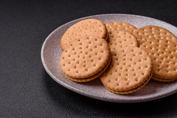 Round dotted snack snack cookies with cream on a dark concrete background