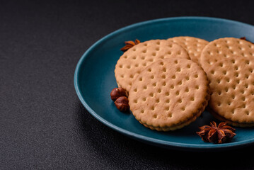 Round dotted snack snack cookies with cream on a dark concrete background