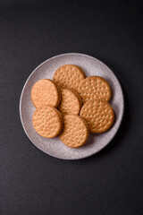 Round dotted snack snack cookies with cream on a dark concrete background