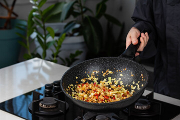 Close up of Chef cook hands cooking roasted onion, pepper, Shiitake mushrooms, cabbage, garlic in frying wok pan on gas stove.