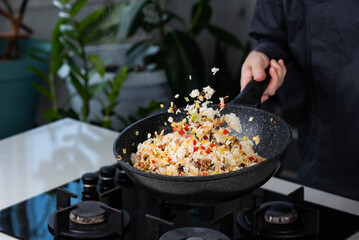 Close up of Chef cook hands cooking and toss roasted vegetables with rice for Asian cuisine in...