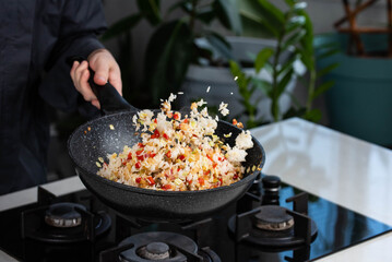 Close up of Chef cook hands cooking and toss roasted vegetables with rice for Asian cuisine in...