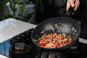 Close up of Chef cook hands cooking roasted onion, pepper, Shiitake mushrooms, cabbage, garlic in frying wok pan on gas stove.