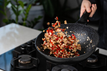 Close up of Chef cook hands cooking and toss roasted onion, pepper, Shiitake mushrooms, cabbage, garlic in frying wok pan on gas stove. Flying food levitation.