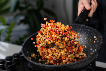 Close up of Chef cook hands cooking and toss roasted onion, pepper, Shiitake mushrooms, cabbage, garlic in frying wok pan on gas stove. Flying food levitation.