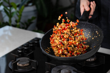 Close up of Chef cook hands cooking and toss roasted onion, pepper, Shiitake mushrooms, cabbage, garlic in frying wok pan on gas stove. Flying food levitation.