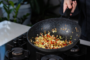 Close up of Chef cook hands cooking roasted onion, pepper, Shiitake mushrooms, cabbage, garlic in frying wok pan on gas stove.