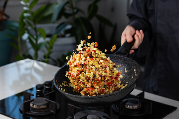 Close up of Chef cook hands cooking and toss roasted onion, pepper, Shiitake mushrooms, cabbage, garlic in frying wok pan on gas stove. Flying food levitation.