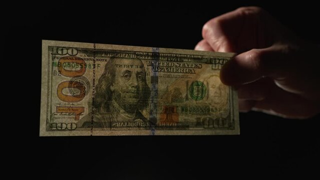 100 dollar banknote shows through light on black background