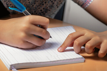 Close nas mãos de uma criança que está escrevendo em um caderno. Conceito de volta às aulas.